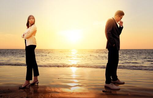Par på strand står med ryggen mod hinanden efter konflikter i et parforhold