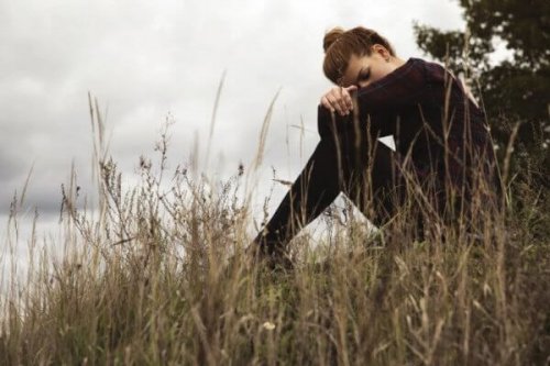 Kvinde sidder alene på eng
