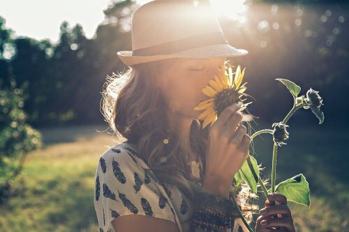 Kvinde dufter til solsikke og afspejler vigtigheden af ​​at afkoble dig selv