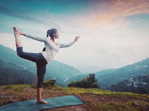 Kvinde dyrker yoga med udsigt over landskab