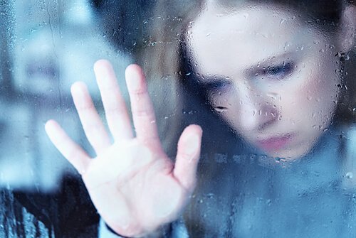 Trist kvinde med hånd på vindue er offer for skam