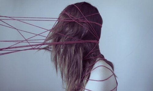 Kvinde er fanget af røde tråde som symbol for kognitive fordomme