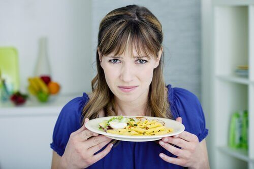 En kvinde, der holder en tallerken med mad og føler afsky