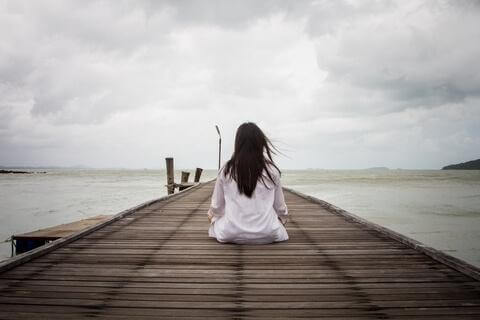 kvinde sidder foran havet og træner kognitiv tålmodighed