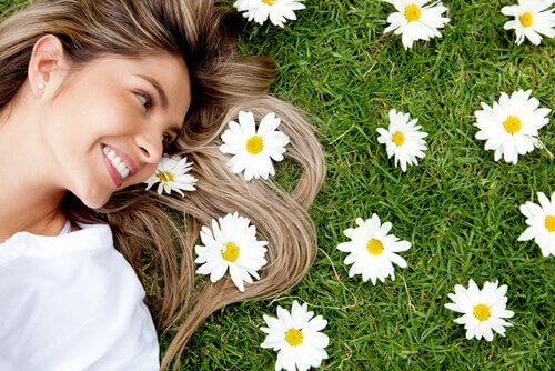 En kvinde ligger ved siden af blomster og smiler
