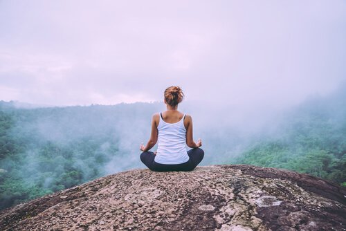 Kvinde mediterer med udsigt over skov