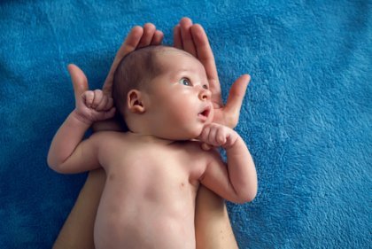 Baby i voksens hænder ser med store øjne