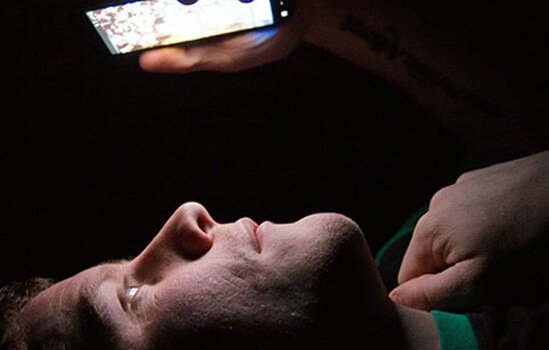 Mand ser på sin mobil i mørket
