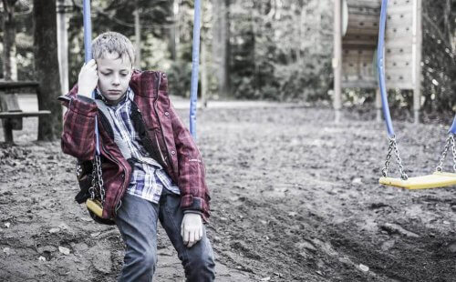 Trist dreng sidder på en gynge og føler, at folk burde vide bedre end til at mobbe