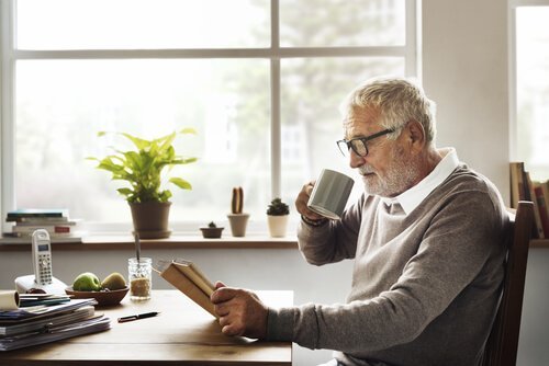 Ældre mand læser, mens han drikker kaffe