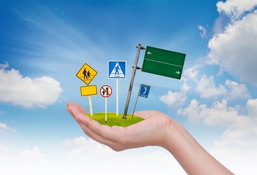 Bedre køreuddannelse illustreres af hånd med vejskilte