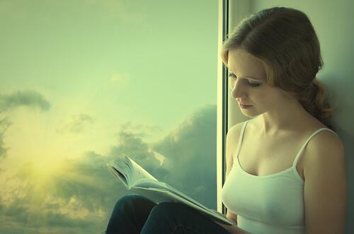 Kvinde læser bog ved vindue