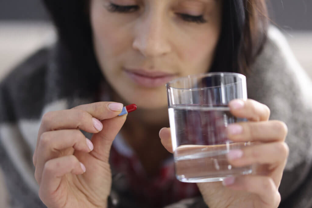 Kvinde med en pille og et glas vand