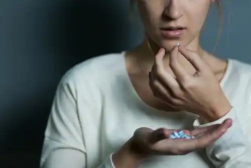 Kvinde tager en pille, hvilket repræsenterer psykofarmakologi