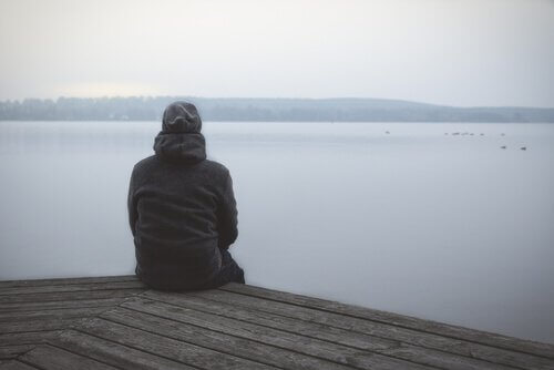 En mand sidder og kigger ud på søen