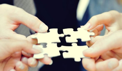 Personer sætter puslespilsbrikker sammen