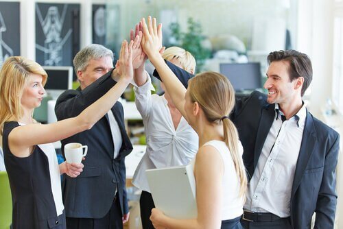 Kolleger giver fælles high five på grund af arbejdsplads engagement