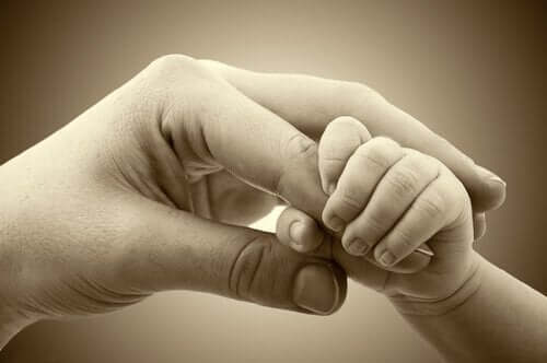 En baby holder sin mors finger
