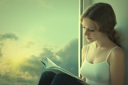 Kvinde læser bog i vindue