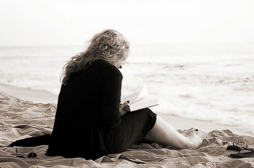Sådan kan litteratur og poesi hjælpe vores velbefindende, når vi læser som denne kvinde på en strand