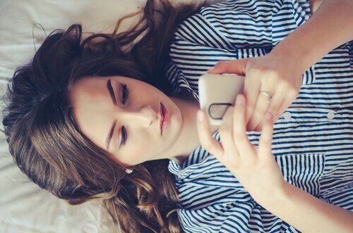 Kvinde på seng med mobil