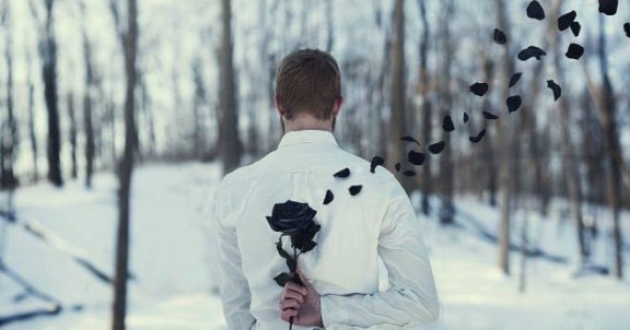 Mand i snelandskab med vissen rose bag ryg