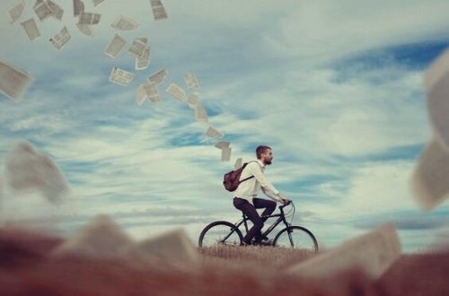 Mand på cykel, der taber en masse papirer