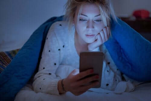 kvinde, der kigger på mobil i seng