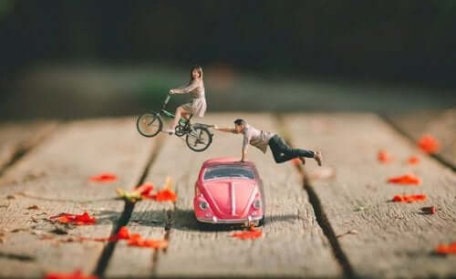 Figur af par, hvor mand rækker ud efter flyvende kvinde på cykel