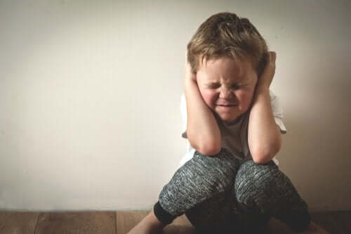 En lille dreng holder sig for ørerne på grund af toksisk stress