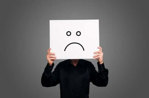 person med papir med sur smiley foran sit ansigt har valgt at være pessimist