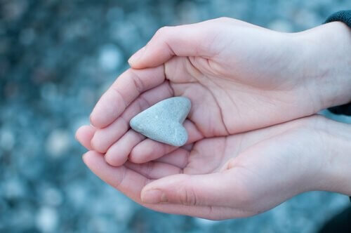 Person holder hjerteformet sten i hænderne 