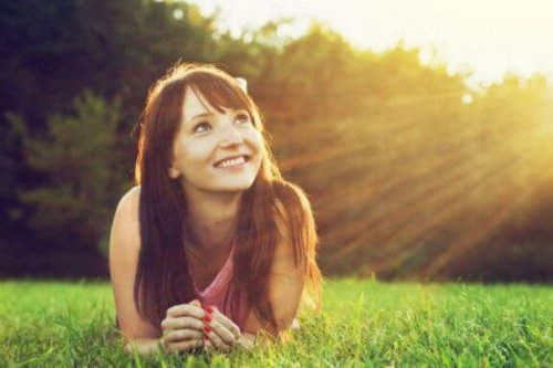 En kvinde smiler og kigger op mod solen