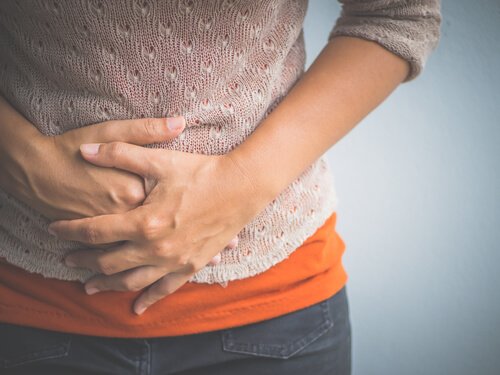 Kvinde, der tager sig til mave, oplever smerter forbundet med de forskellige faser i en menstruationscyklus
