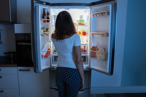kvinde foran et åbent køleskab er nattespiser