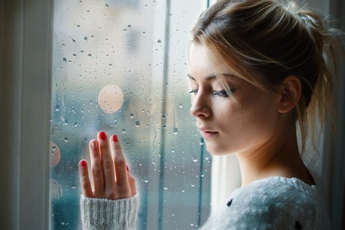 En kvinde med negative følelser står ved vindue