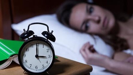 Kvinde, der kigger på ur, kan ikke sove