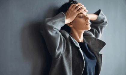 Træt kvinde tager sig til hoved i frustration over, hvor let noget bliver til en vane