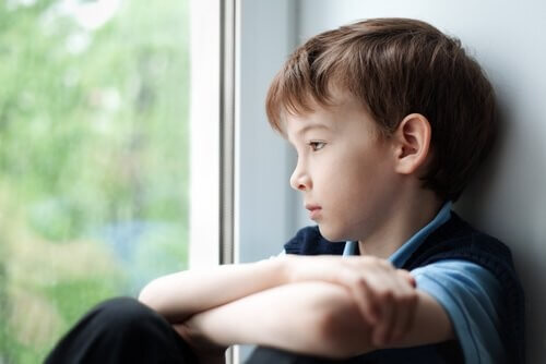 En trist dreng kigger ud af vinduet