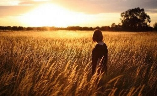 Kvinde ser solnedgangen på en mark og tænker over sammenhængen mellem selvopfattelse og depression