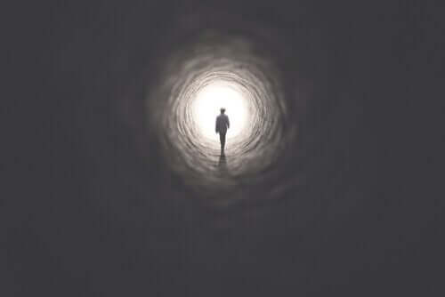 Person går mod lys i mørk tunnel