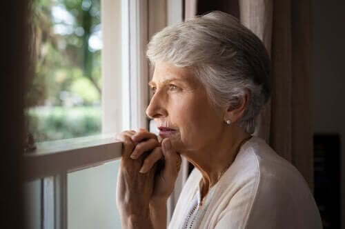 Ældre kvinde ser ud af vindue