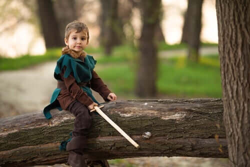 dreng, der sidder på træ, klædt ud som Robin Hood