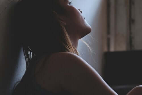 kvinde, der sidder op ad væg i mørke