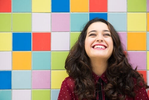 Kvinde smiler foran en farverig baggrund
