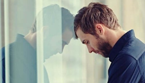 trist mand, der læner sig op ad vindue