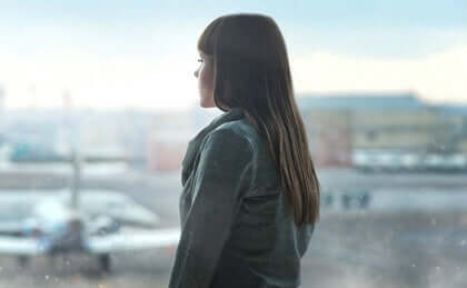 En kvinde, der kigger ud af vinduet i en lufthavn