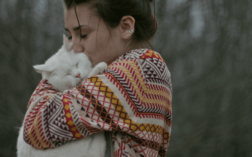 Kvinde krammer en kat i skov