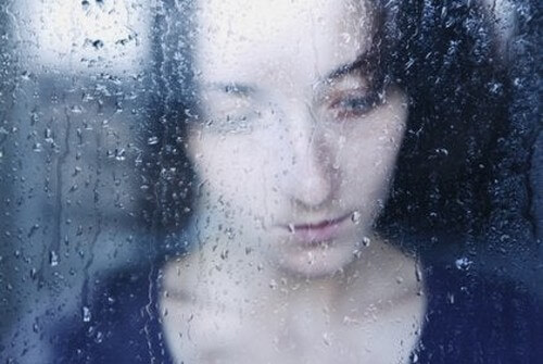 Trist kvinde bag våd rude lider under narcissisme i et forhold