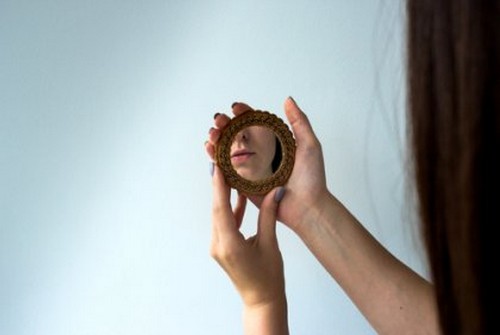 Kvinde, der ser sig i spejl, symboliserer narcissisme i et forhold